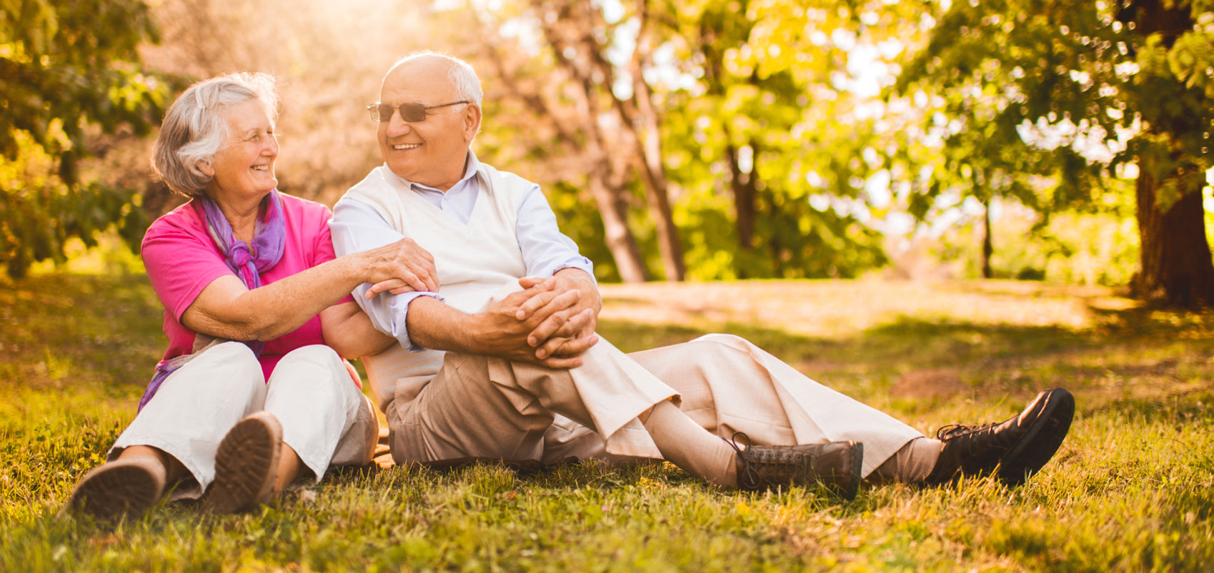 Senior couple sitting on grass in a park