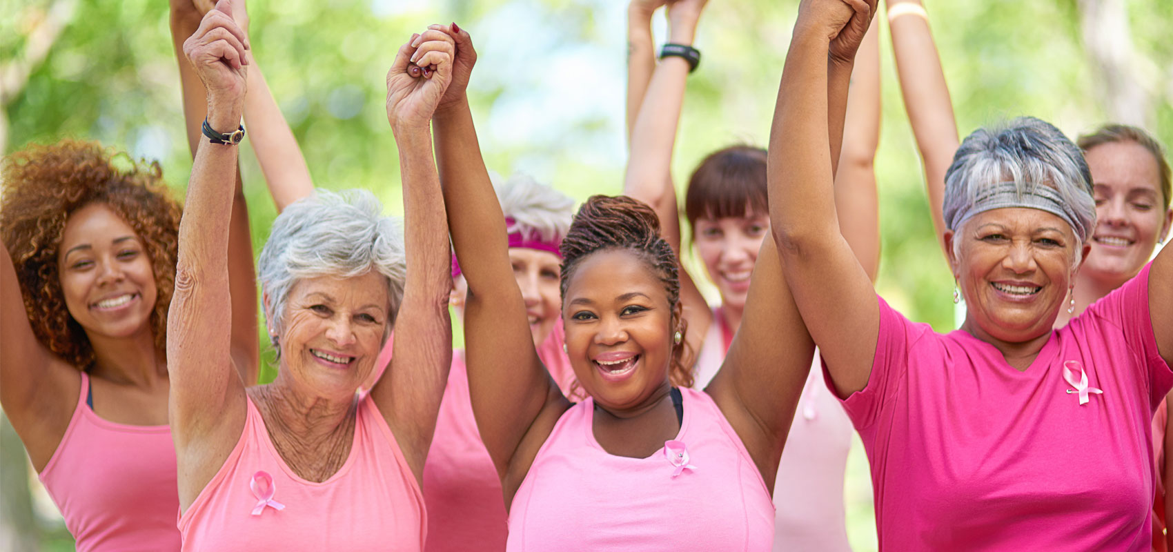 Women wearing pink and holding up hands for breast cancer awareness