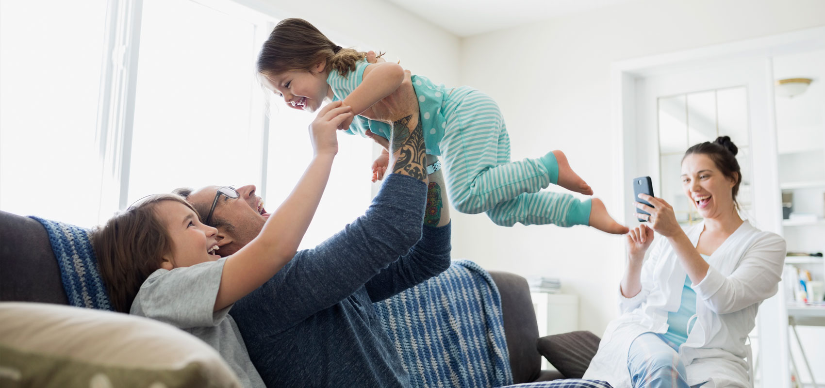 Grandma and Grandpa holding up granddaughter on couch while mom takes a photo